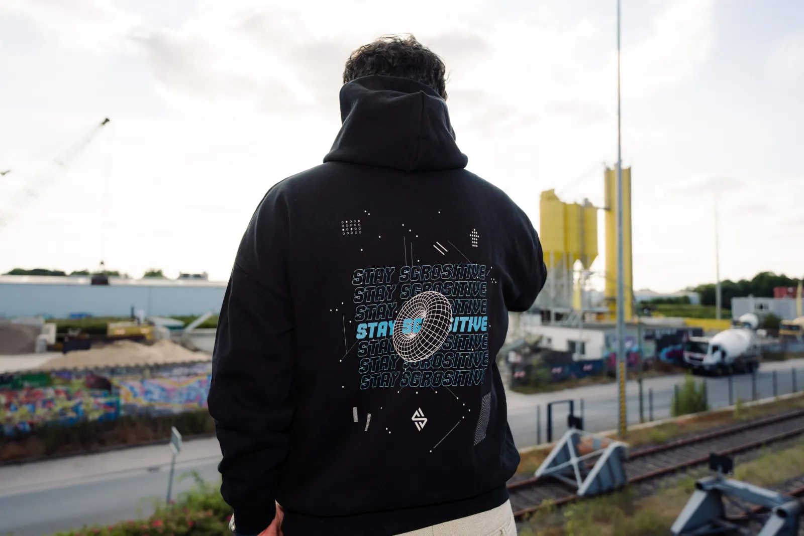 Pasquale von hinten mit Hoodie-Backprint vor den gelben Silos